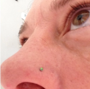 G23 titanium L-shaped nose stud with green opal zircon gemstone on a female model