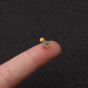 Close-up of golden square stud earring with zircon and screw back held on a fingertip