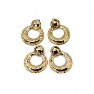Detailed view of two pairs of vintage gold hammer-textured round metal earrings on white background
