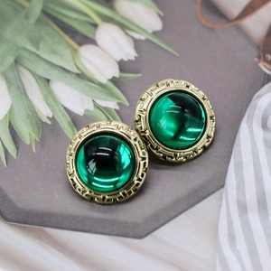 Close-up of vintage gold relief earrings featuring elegant round green resin gemstones