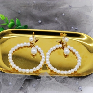 Detailed view of elegant gold drop earrings featuring white pearls and a beaded hoop
