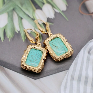 Detailed macro view of vintage gold earrings with textured trim and green stone inlay