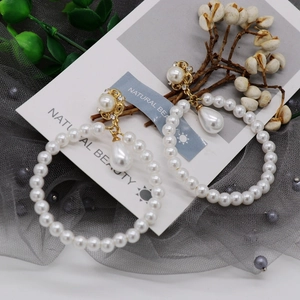 Macro shot of pearl drop earrings with gold alloy frame and crystal studs on mesh background