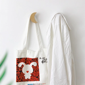 Nordic wooden wall hooks in moon shape holding a white canvas bag on a clean white wall