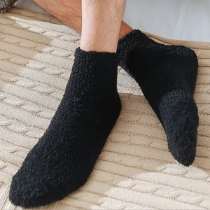 Thick warm black coral fleece sleep socks for men on a soft beige knit blanket