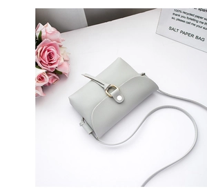 Detail of grey crossbody bag with gold ring buckle and elegant floral decoration