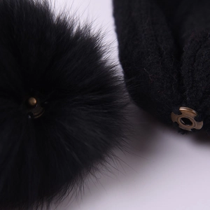 Black knit hat with detachable faux fox fur pompom showing the bronze metal snap button