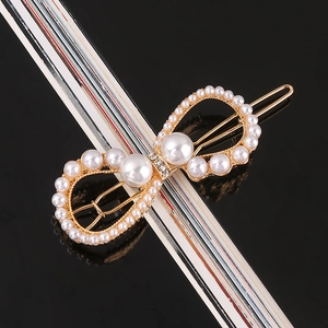Close-up of handmade bow hair clip with white pearls and crystals on gold alloy base