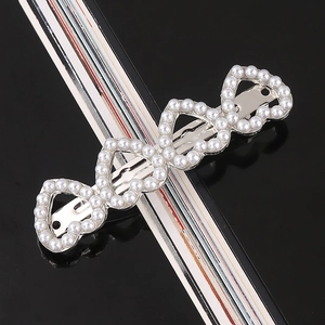 Detail of silver barrette with white faux pearls in interlocking heart geometry