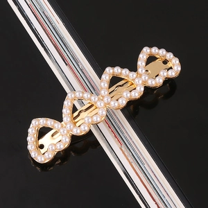 Close-up of elegant gold alloy heart-shaped hair clip with white faux pearls
