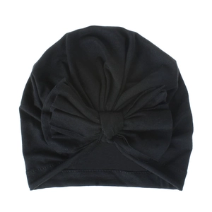 Dettaglio di un turbante nero per neonati con un grande fiocco decorativo in cotone