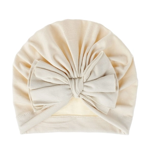 Dettaglio del cappello a turbante crema per neonati con grande fiocco in maglia