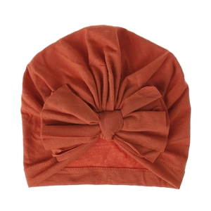Dettaglio del turbante per neonati rosso caramello con un morbido fiocco in cotone a coste