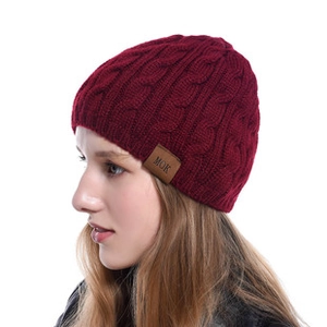 Detailed close-up of dark burgundy cable knit headband featuring a brown leather label