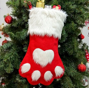Red dog paw Christmas stocking with white plush trim hanging on a festive Xmas tree