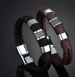 Detail of black and brown woven leather bracelets with polished metal decorative rings