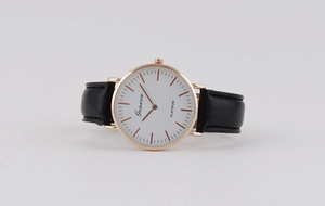 Detail of minimalist quartz watch with rose gold case, white dial, and black leather strap