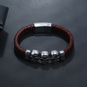 Detail view of brown braided leather bracelet with silver skull charms and magnetic clasp