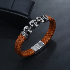 Men's brown woven leather bracelet featuring silver metal skull charms and magnetic clasp