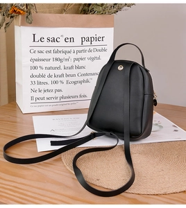 Detail view of the black PU leather backpack back with adjustable straps on a wooden table