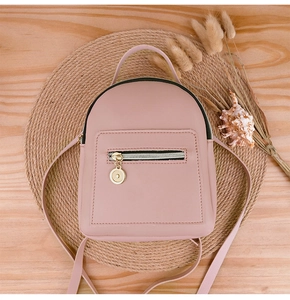 Close-up of pink mini backpack with golden zippers on a rustic straw mat background