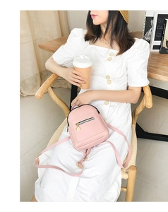 Pink mini faux leather backpack with gold zipper detail shown in a cozy lifestyle setting