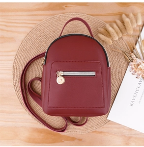 Detail view of deep red mini backpack in soft PU leather with gold zipper accents