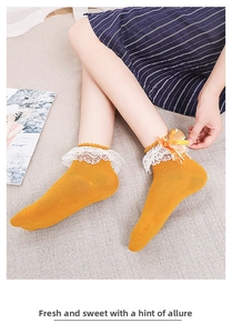 Detail of ginger cotton socks featuring delicate white lace trim and silk ribbon bows