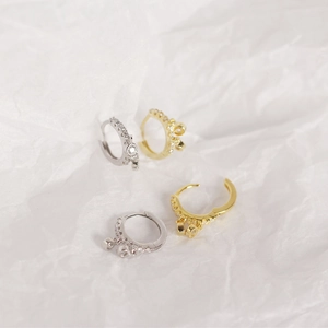 Detail of silver and gold huggie hoop earrings with sparkling charms on white texture