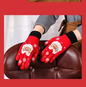 Detail of red Christmas knit gloves featuring Santa Claus patterns on a brown leather chair