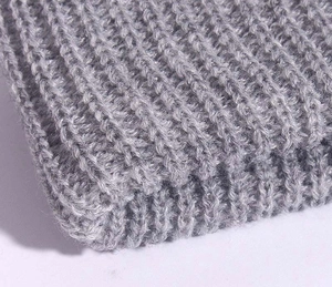 Macro shot of grey knit beanie fabric showing detailed stitch texture and warm wool yarn