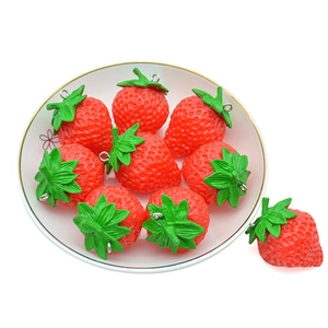 Realistic PVC strawberry keychains with green leaves and silver rings on a floral plate