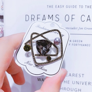 High-end geometric brooch with dark faceted gemstone and pearls on display card