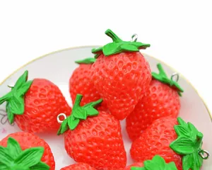 Macro shot of realistic PVC strawberry pendants with metal rings on a white plate