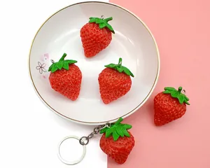 Detailed view of realistic PVC strawberry pendants with green leaves and metal keychains