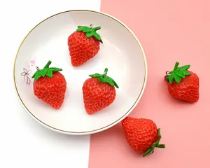 Detailed view of realistic PVC strawberry pendants with textured surface and metal rings