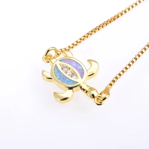 Macro shot of gold turtle necklace with opal shell and cubic zirconia details