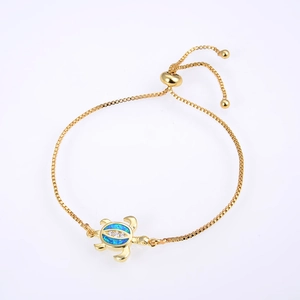 Macro detail of gold turtle bracelet featuring blue opal stone and adjustable box chain