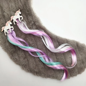 Detail view of two unicorn hair clips with colorful wavy glitter hair extensions for girls