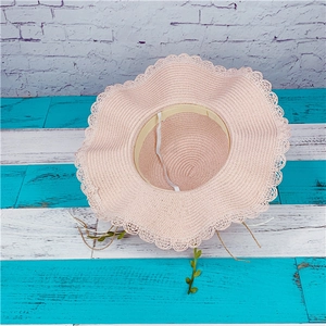 Pink wide-brim straw sun hat with wavy hollow edge and chin strap for beach vacation
