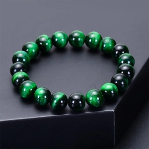 Macro detail of natural green tiger eye stone beads with cat eye effect on grey stand