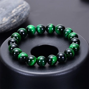 Macro detail of green tiger eye stone beads on a sleek matte black display base