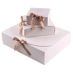 Three white paper gift boxes stacked with elegant gold ribbon bows for luxury packaging