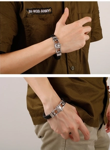 Detail view of men's black braided leather bracelet featuring a silver lion head charm