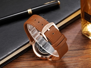 Detail of brown leather watch strap with rose gold buckle and engraved TOMI brand logo