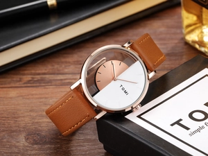Detail of hollow see-through watch with rose gold case and brown leather strap on a desk