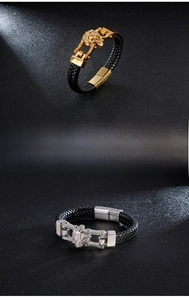 Detail of lion head clasps on braided leather bracelets in gold and silver finishes