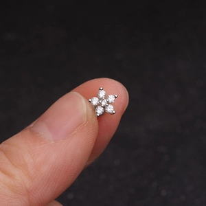 Close-up of a small flower-shaped ear stud featuring sparkling cubic zirconia crystals
