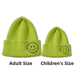 Detailed knit texture of green parent-child beanies with embroidered smiley face patches