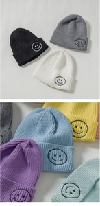 Close-up of the knitted beanie texture featuring a minimalist black embroidered smiley face
